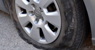 Wie man einen Reifen wechseltEin platter Reifen auf der Straße.