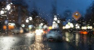 Wie kann man bei Regen fahren. Auto auf der Straße durch Glas gesehen, unscharf.