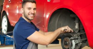 Ein Mechaniker repariert ein rotes Fahrzeug.